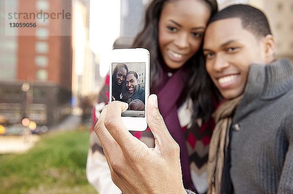 Glückliches junges Paar  das mit einem Smartphone auf sich selbst klickt