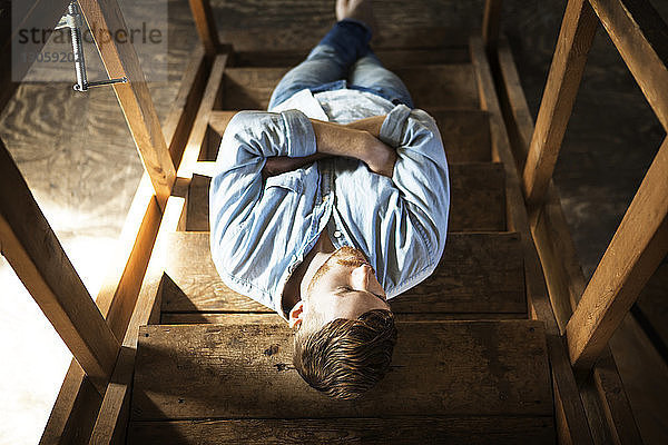 Hochwinkelaufnahme eines Mannes  der sich zu Hause auf einer Treppe entspannt