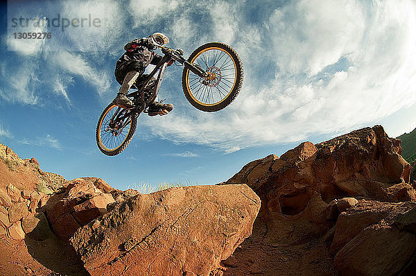 Niedrigwinkelansicht eines Mountainbikers  der beim Radfahren einen Stunt macht