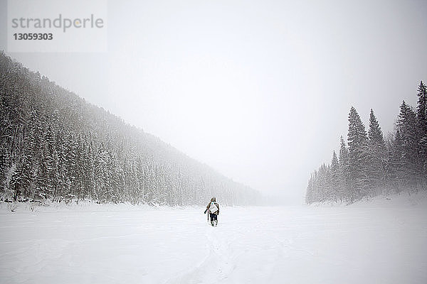 Rückansicht eines Wanderers  der auf einem schneebedeckten Feld geht