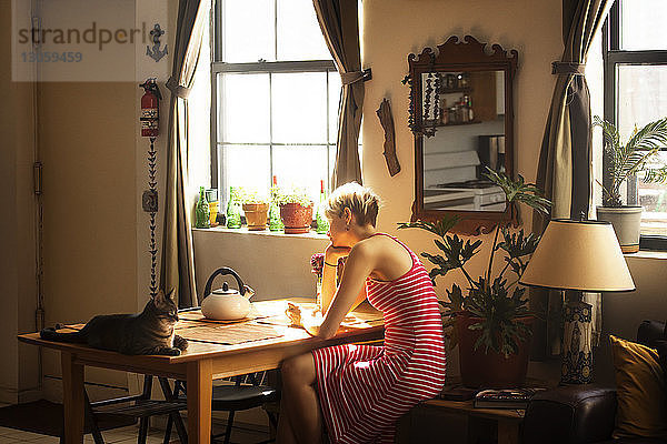Seitenansicht einer Frau  die zu Hause am Tisch sitzt