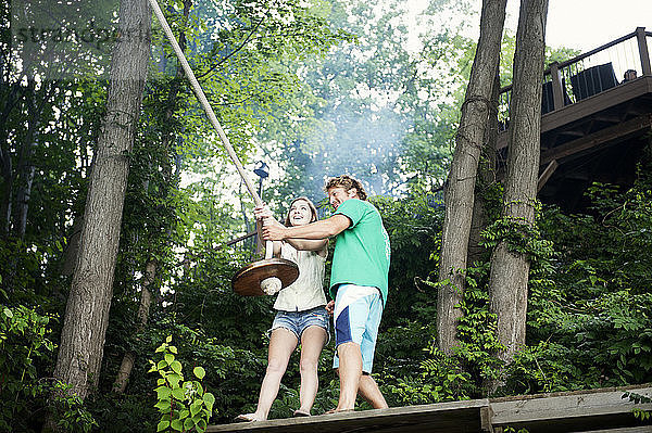 Niedrigwinkelansicht eines glücklichen Paares mit Seilschaukel im Wald