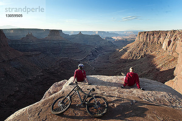 Rückansicht von Mountainbikern  die sich auf einer Klippe gegen den Himmel entspannen