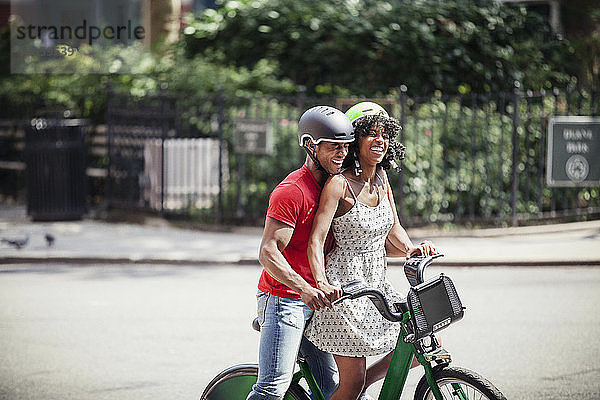 Fröhliches Paar mit Fahrrad auf der Straße in der Stadt stehend