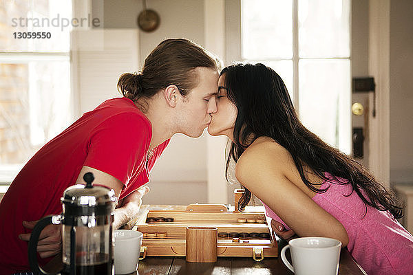 Leidenschaftliches Paar küsst sich am Tisch