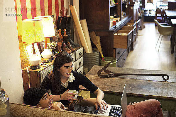 Paar benutzt Laptop-Computer  während es sich im Café auf dem Sofa entspannt