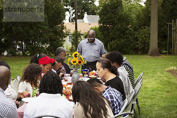 Familie und Freunde essen bei Tisch im Hinterhof