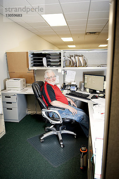 Seitenansicht eines auf einem Stuhl sitzenden Geschäftsmannes im Büro