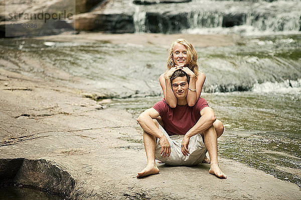 Porträt eines auf Felsen sitzenden Paares am Flussufer