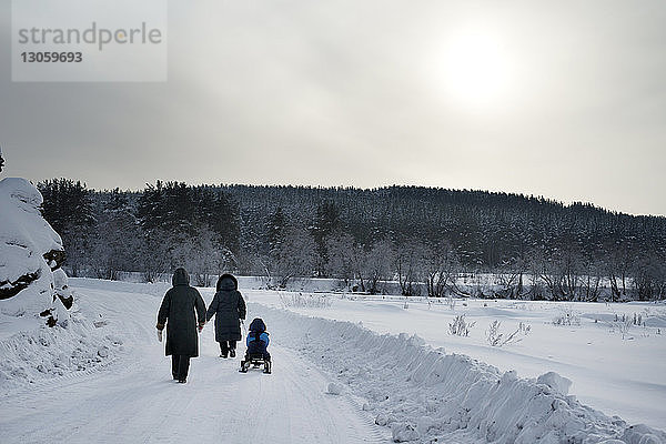 Rückansicht der Familie auf schneebedecktem Feld gegen den Himmel