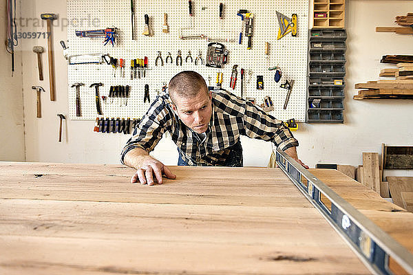 Zimmermann prüft Holz mit Geräten in der Werkstatt