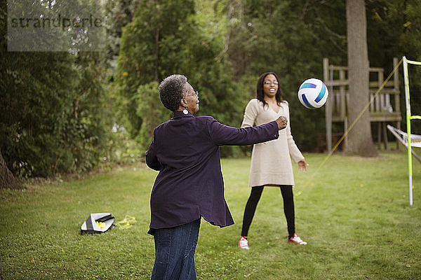 Ältere Frau und Enkelin spielen mit dem Ball im Hinterhof