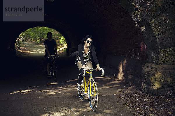 Freunde radeln auf der Straße unter dem Tunnel