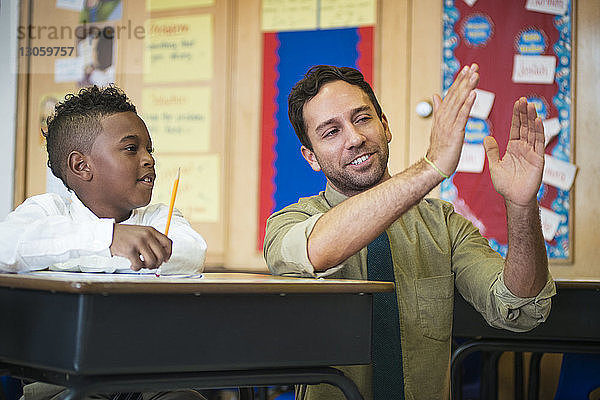 Glückliche Lehrerin erklärt dem Jungen im Klassenzimmer