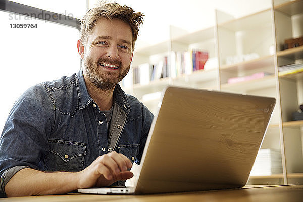 Porträt eines glücklichen Mannes mit Laptop zu Hause