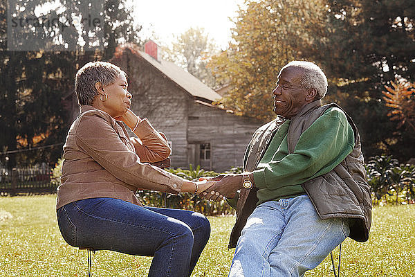 Romantisches älteres Paar  das im Hinterhof sitzend Händchen hält