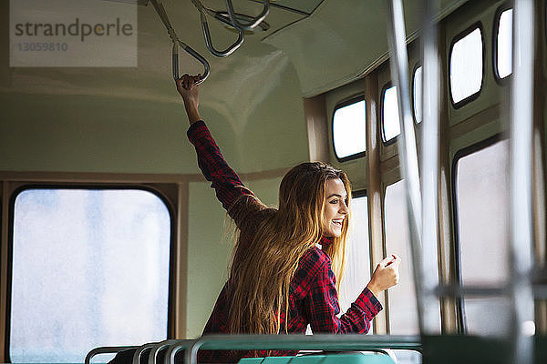 Glückliche Frau schaut durch Straßenbahnfenster
