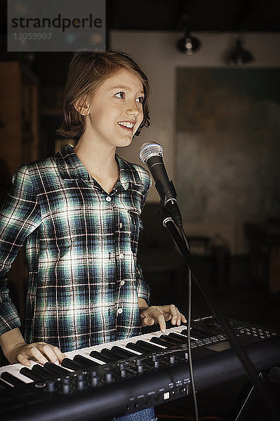 Glückliches Mädchen singt und spielt Klavier