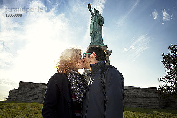 Ein Paar küsst sich  während es gegen die Freiheitsstatue steht