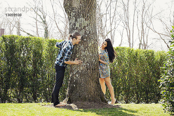 Ehepaar steht um einen Baum im Rasen