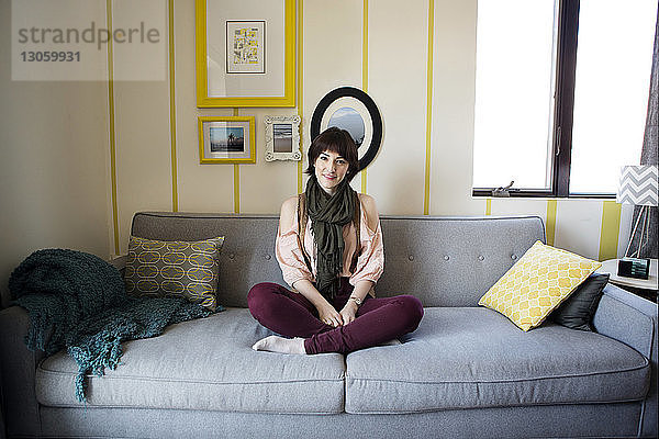 Porträt einer lächelnden schönen Frau  die zu Hause auf dem Sofa sitzt