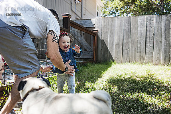 Glückliche Familie mit Hund spielt im Garten