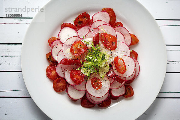 Draufsicht auf Radieschen- und Tomatensalat  der auf dem Tisch serviert wird