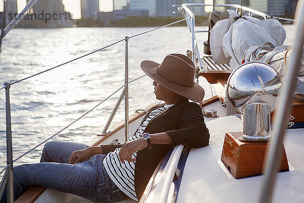 Seitenansicht eines auf einer Yacht sitzenden Mannes mit Cowboyhut