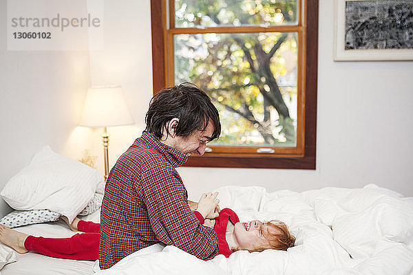 Mann spielt mit Sohn auf Bett im Schlafzimmer