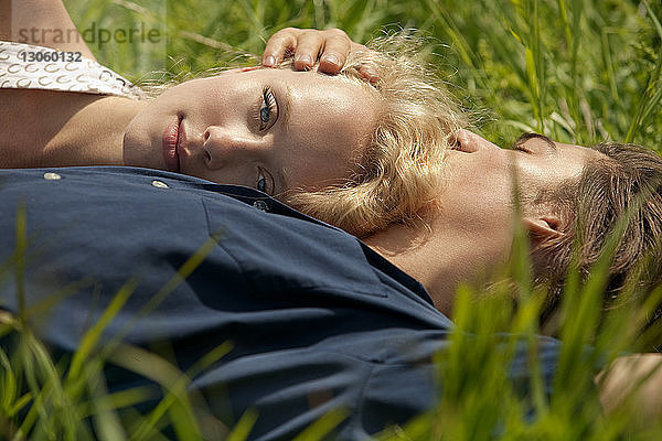Porträt einer Frau  die sich auf der Brust eines Mannes stützt  während sie im Grasfeld liegt