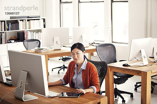Porträt einer Frau  die im Büro am Computer sitzt