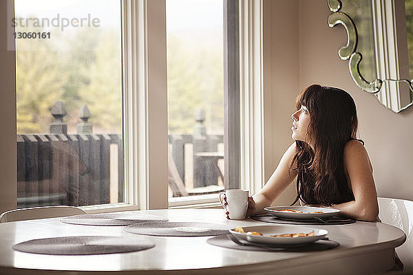 Frau schaut weg  wenn sie zu Hause am Frühstückstisch sitzt
