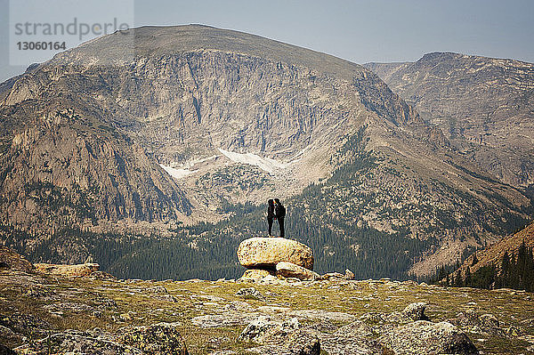 Paar  das sich küsst  während es auf einem Felsen gegen Berge steht
