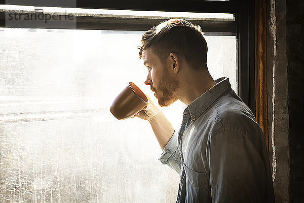 Mann schaut beim Kaffeetrinken weg