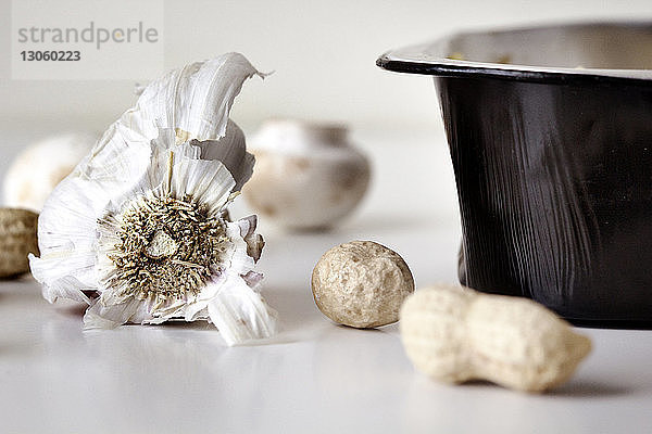 Nahaufnahme von Knoblauch und Erdnüssen auf weißem Tisch