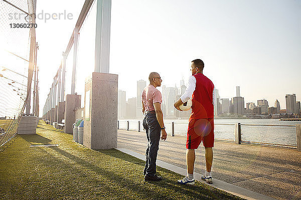 Mann hält Ball in der Hand  während er mit seinem Vater auf dem Fußballplatz am East River in der Stadt spricht