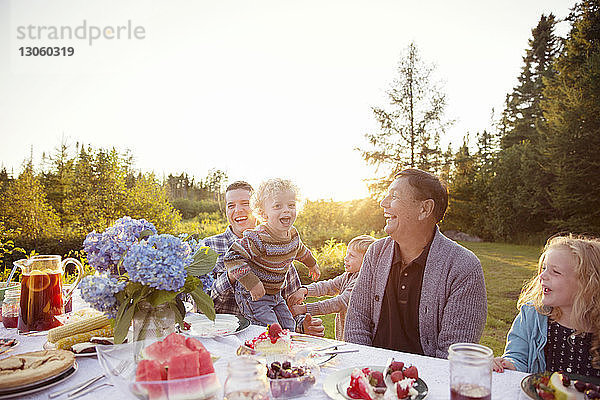 Fröhliche Familie genießt am Picknicktisch an einem sonnigen Tag