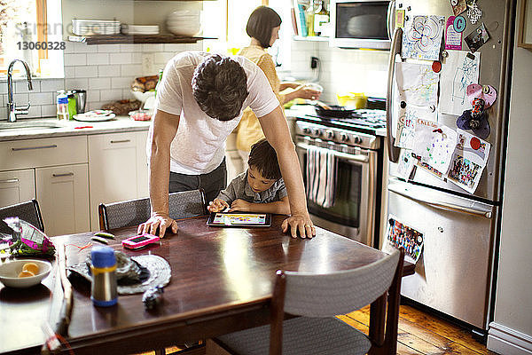 Vater und Sohn benutzen Tablet-Computer am Esstisch in der Küche