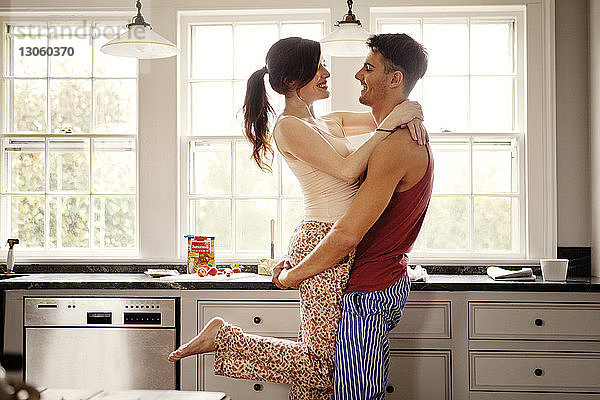 Glückliches Paar umarmt sich  während es zu Hause in der Küche steht