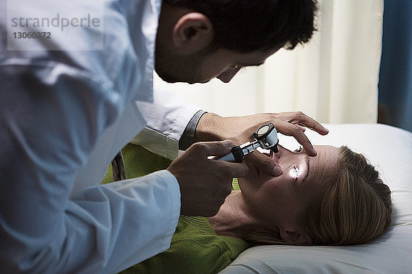 Arzt untersucht das Auge des Patienten im Krankenhaus mit dem Otoskop