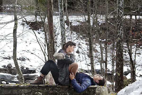 Paar auf Stützmauer im Wald