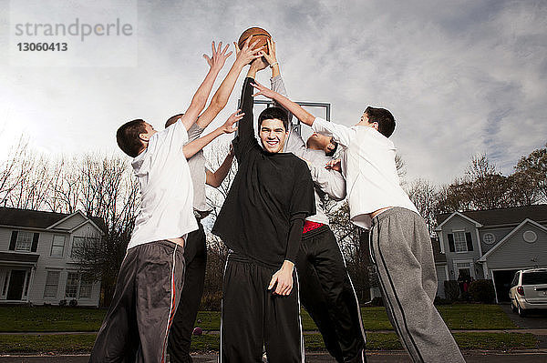 Glückliche Jungen spielen Basketball auf der Straße