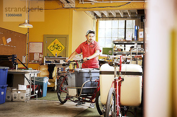 Mann mit Container auf Fahrrad in Werkstatt