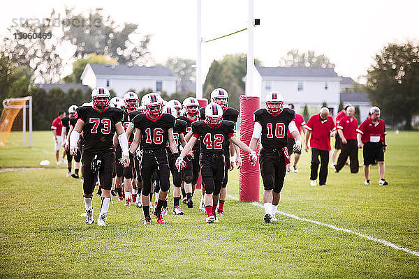 American-Football-Team geht bei Sonnenschein auf dem Spielfeld