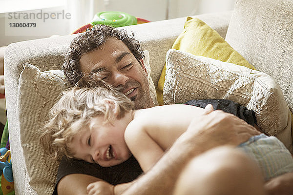 Glücklicher Vater und Tochter liegen zu Hause auf dem Sofa