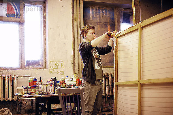 Künstler befestigt Leinwand auf Holzrahmen in einem Workshop