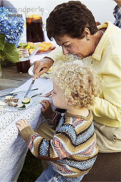 Hochwinkelansicht einer Großmutter  die ihren Enkel auf einem Picknicktisch füttert