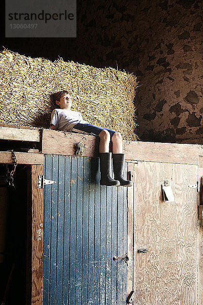 Junge entspannt im Heu auf Holzkonstruktion