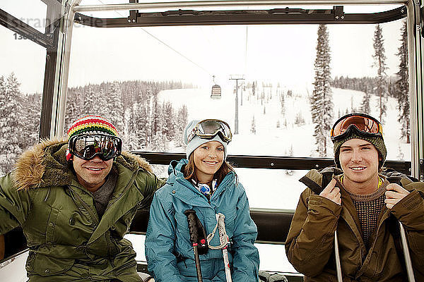 Porträt von glücklichen Skifahrern  die in der Luftseilbahn sitzen