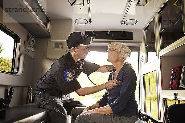Sanitäter untersuchen Patient mit Stethoskop  während sie im Krankenwagen sitzen